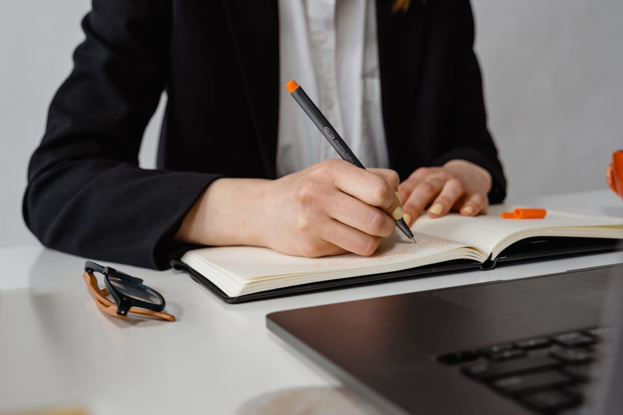 Молодой специалист делает заметки в ежедневнике за рабочим столом